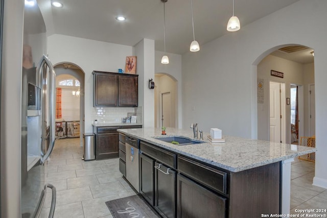 kitchen featuring sink, an island with sink, decorative light fixtures, dark brown cabinets, and appliances with stainless steel finishes