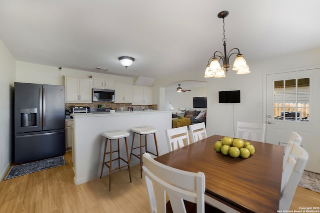 dining room featuring light hardwood / wood-style flooring and ceiling fan with notable chandelier