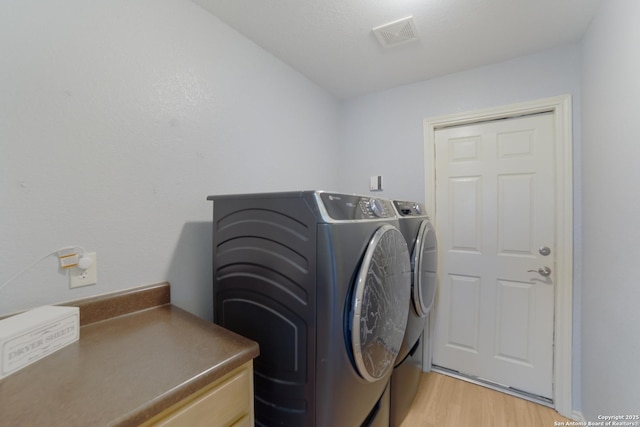 laundry room featuring independent washer and dryer and light hardwood / wood-style floors