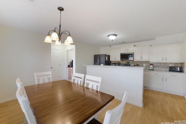 dining room featuring light wood-type flooring and an inviting chandelier