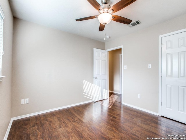 unfurnished bedroom with ceiling fan and dark wood-type flooring