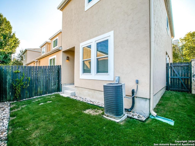 exterior space featuring central AC unit and a lawn