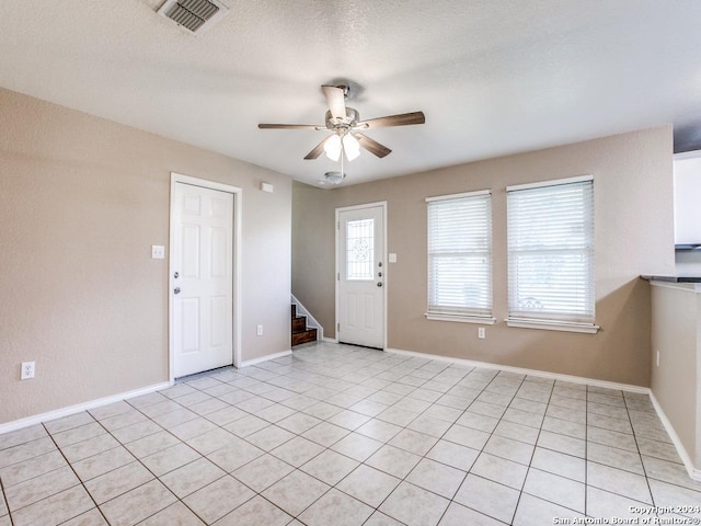 foyer with a textured ceiling, ceiling fan, and light tile patterned flooring