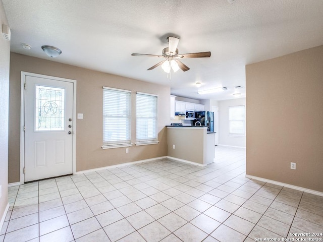 entrance foyer featuring ceiling fan, light tile patterned flooring, and a healthy amount of sunlight