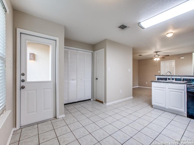 kitchen with ceiling fan, sink, black dishwasher, white cabinetry, and light tile patterned flooring