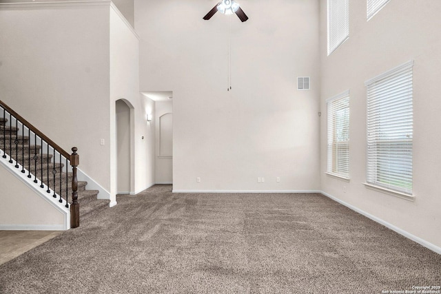 unfurnished living room with a towering ceiling, carpet floors, and ceiling fan