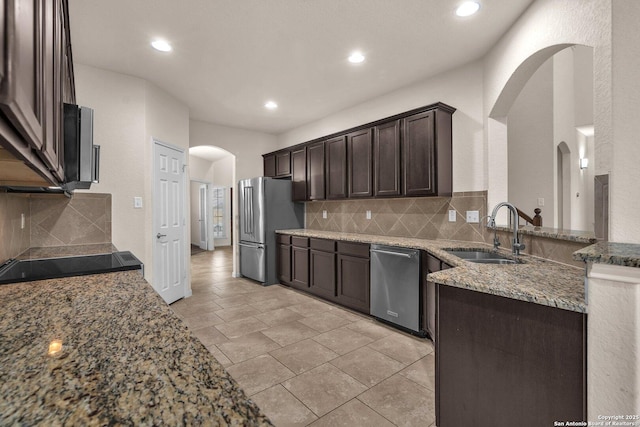 kitchen with light stone countertops, sink, stainless steel appliances, decorative backsplash, and dark brown cabinets