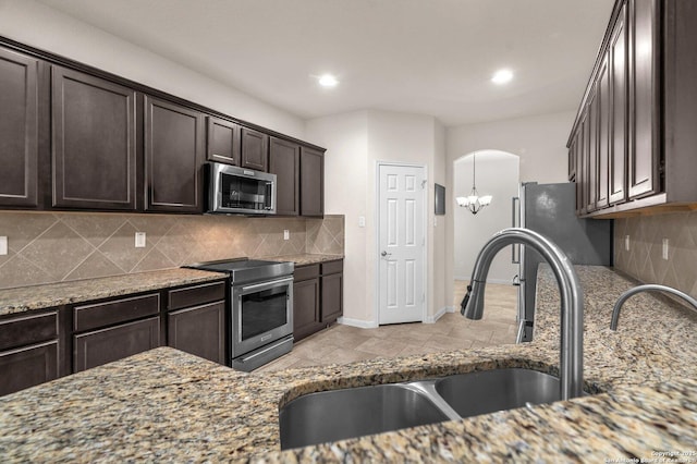 kitchen with decorative backsplash, light stone countertops, sink, and appliances with stainless steel finishes