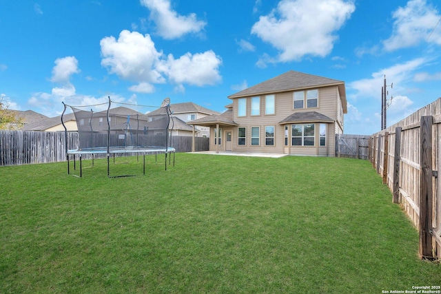 rear view of house featuring a yard and a trampoline