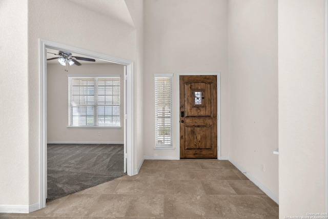 foyer featuring ceiling fan and light colored carpet