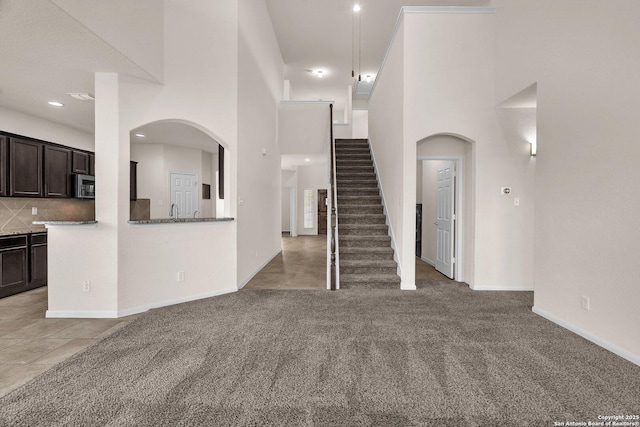 unfurnished living room with carpet, a towering ceiling, and sink