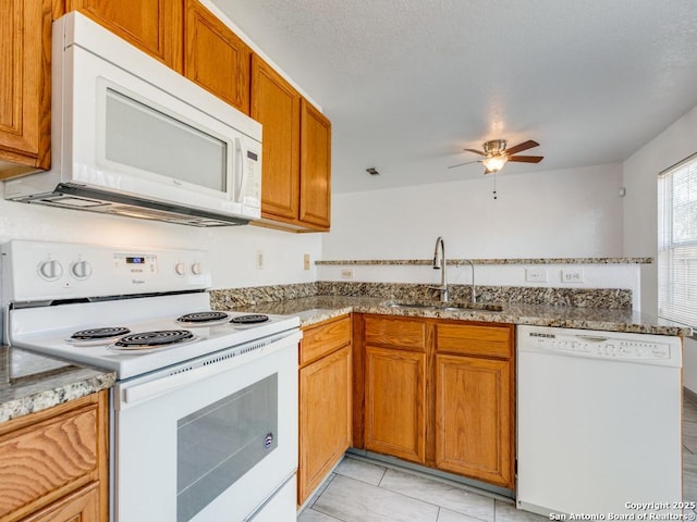 kitchen featuring kitchen peninsula, white appliances, ceiling fan, sink, and stone counters