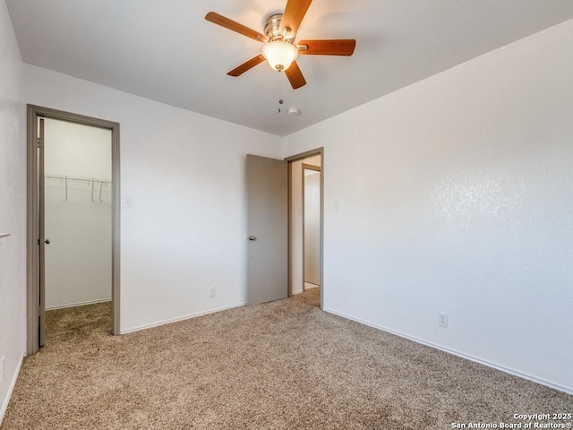 unfurnished bedroom featuring ceiling fan, light colored carpet, a spacious closet, and a closet