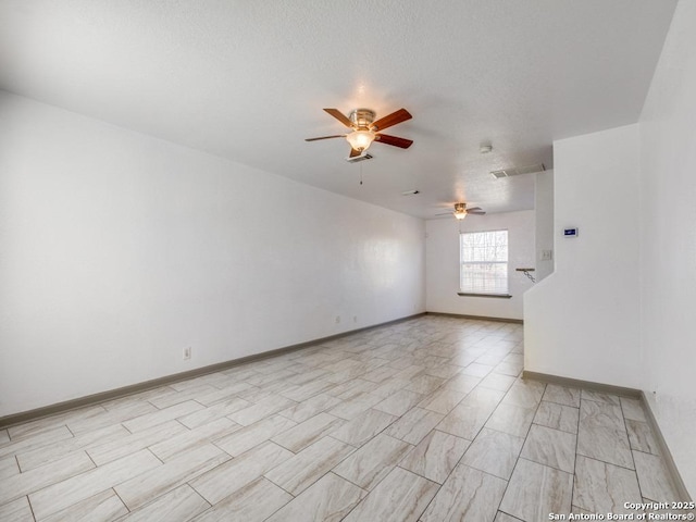 empty room with ceiling fan and a textured ceiling