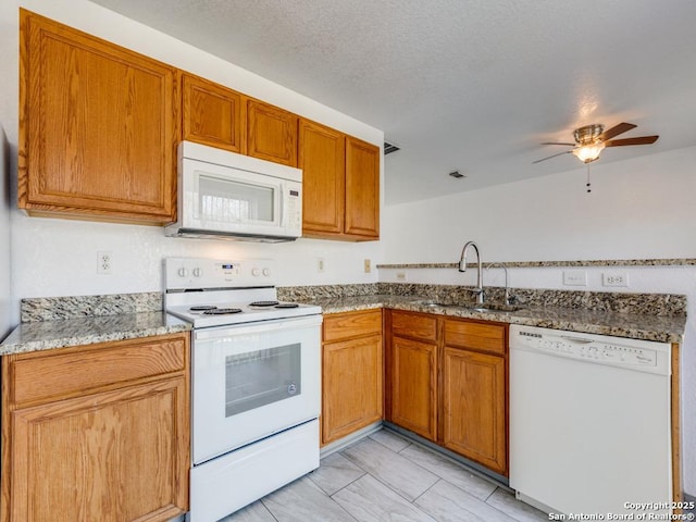 kitchen with white appliances, stone counters, sink, ceiling fan, and a textured ceiling