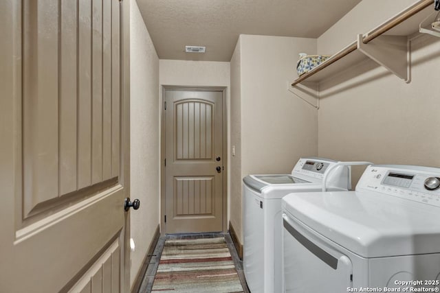 laundry area with a textured ceiling and independent washer and dryer