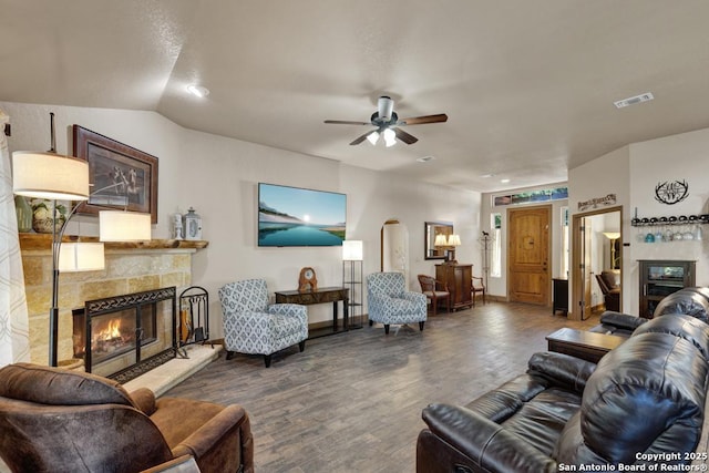 living room featuring ceiling fan, dark hardwood / wood-style flooring, and a fireplace