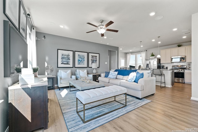 living room featuring light hardwood / wood-style floors and ceiling fan