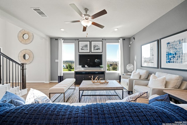 living room with light wood-type flooring, plenty of natural light, and ceiling fan