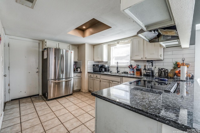 kitchen with light tile patterned flooring, sink, stainless steel fridge, tasteful backsplash, and stovetop