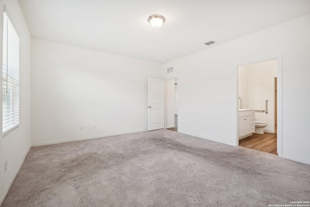 unfurnished bedroom with light carpet and connected bathroom