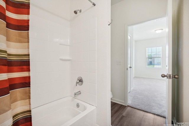 bathroom with hardwood / wood-style flooring and shower / bathtub combination with curtain