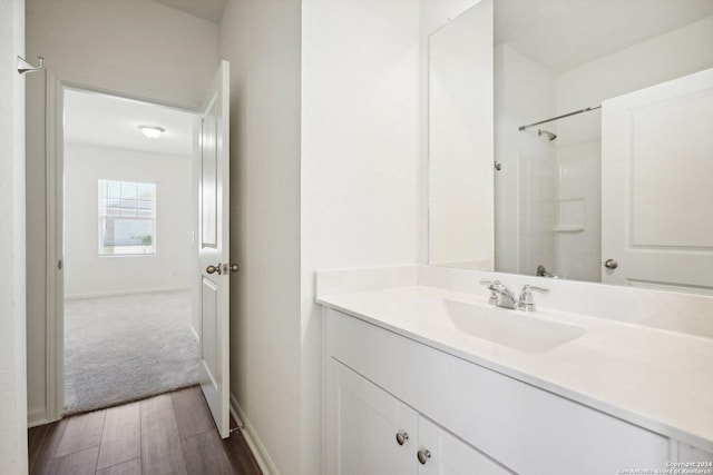 bathroom featuring a shower, hardwood / wood-style floors, and vanity