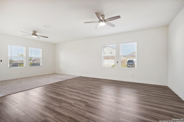 spare room featuring ceiling fan, a healthy amount of sunlight, and dark wood-type flooring