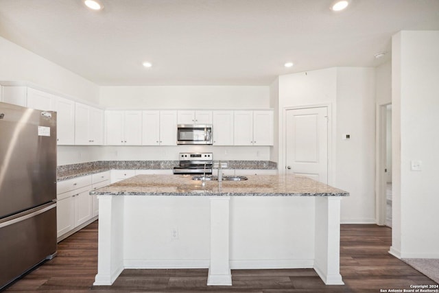 kitchen featuring light stone counters, stainless steel appliances, white cabinetry, and an island with sink