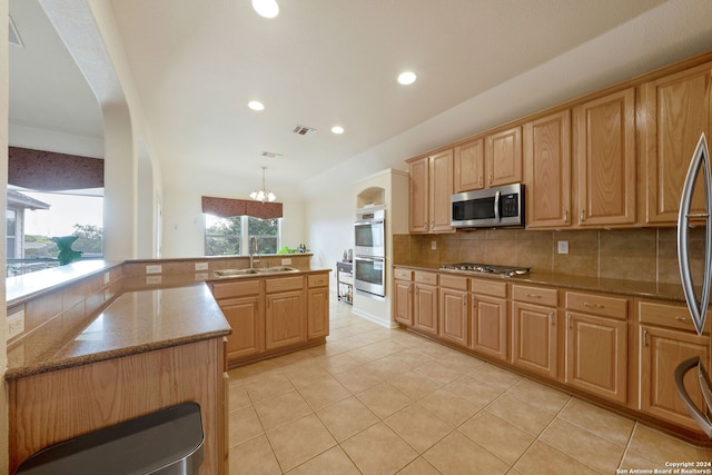 kitchen with pendant lighting, backsplash, sink, appliances with stainless steel finishes, and a chandelier