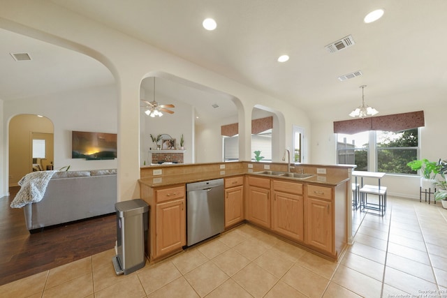 kitchen with sink, stainless steel dishwasher, decorative light fixtures, light tile patterned flooring, and ceiling fan with notable chandelier