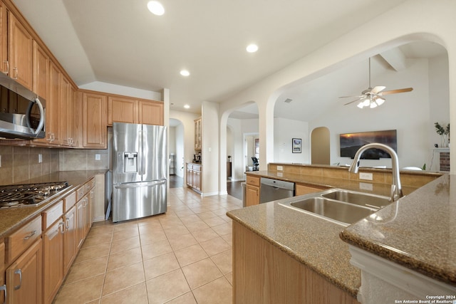 kitchen with appliances with stainless steel finishes, tasteful backsplash, dark stone counters, sink, and lofted ceiling with beams