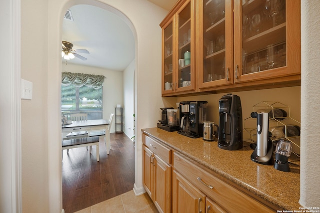 bar featuring light stone countertops, light tile patterned floors, and ceiling fan