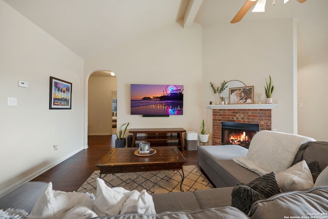 living room with vaulted ceiling with beams, ceiling fan, dark hardwood / wood-style flooring, and a brick fireplace