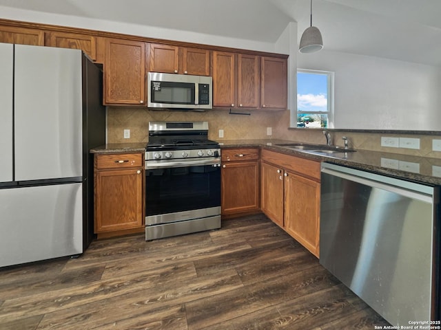 kitchen featuring backsplash, dark wood-type flooring, sink, appliances with stainless steel finishes, and decorative light fixtures