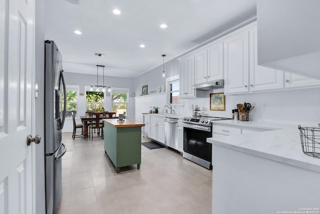 kitchen with white cabinetry, a kitchen island, stainless steel appliances, and wood counters