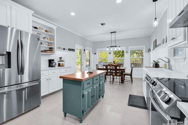 kitchen featuring wall chimney exhaust hood, stainless steel appliances, wood counters, white cabinets, and a kitchen island