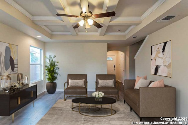 living room with ceiling fan, coffered ceiling, beamed ceiling, wood-type flooring, and ornamental molding