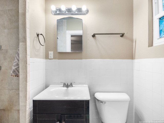 bathroom featuring vanity, toilet, and tile walls