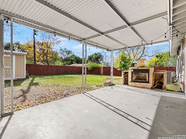 view of patio featuring central air condition unit, exterior fireplace, and a storage unit