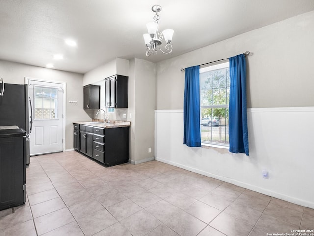 kitchen with stainless steel appliances, sink, pendant lighting, a chandelier, and light tile patterned flooring