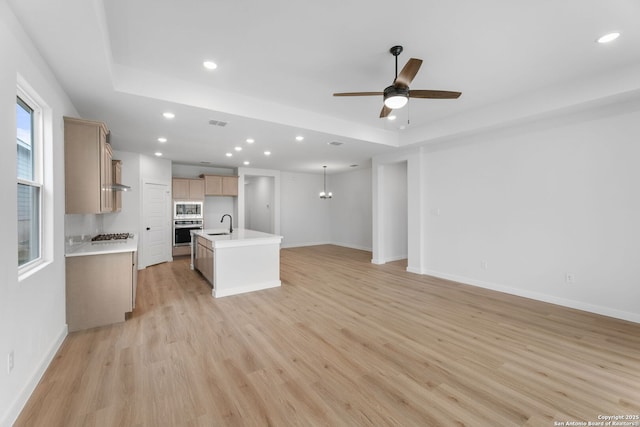 kitchen featuring open floor plan, a tray ceiling, recessed lighting, a ceiling fan, and appliances with stainless steel finishes