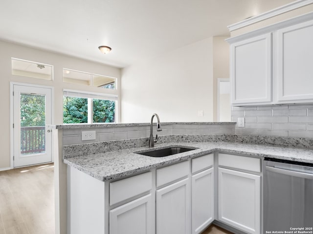 kitchen with decorative backsplash, light stone countertops, sink, dishwasher, and white cabinetry