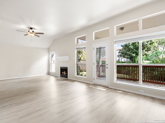 unfurnished living room with ceiling fan, plenty of natural light, vaulted ceiling, and light wood-type flooring