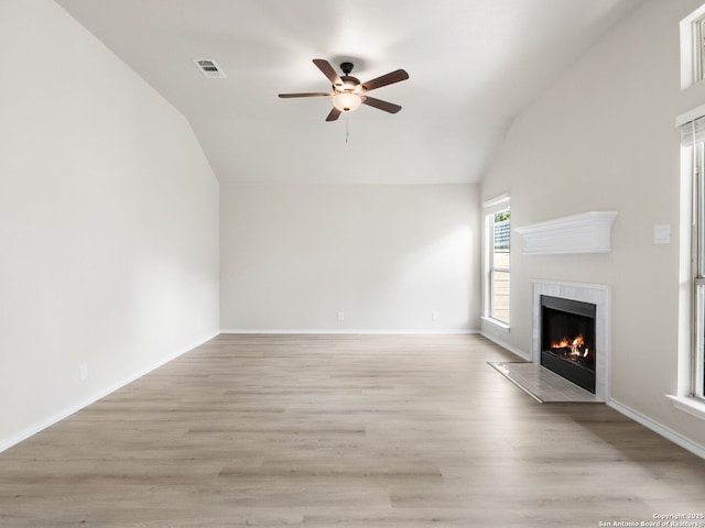 unfurnished living room featuring ceiling fan, light wood-type flooring, a fireplace, and vaulted ceiling