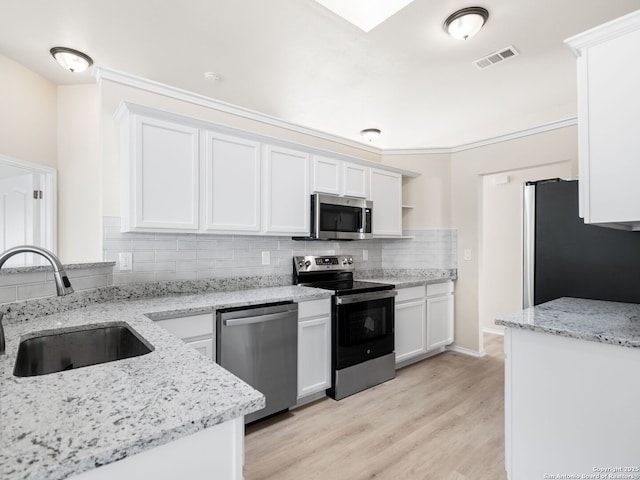 kitchen featuring appliances with stainless steel finishes, light stone counters, sink, light hardwood / wood-style flooring, and white cabinetry