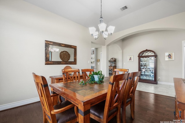 dining area featuring dark wood-type flooring and a notable chandelier