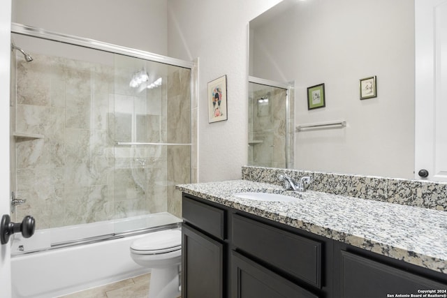 full bathroom with shower / bath combination with glass door, tile patterned floors, vanity, and toilet