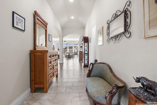 hallway featuring light tile patterned floors and lofted ceiling