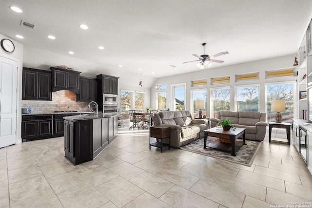 living room featuring vaulted ceiling, ceiling fan, and sink